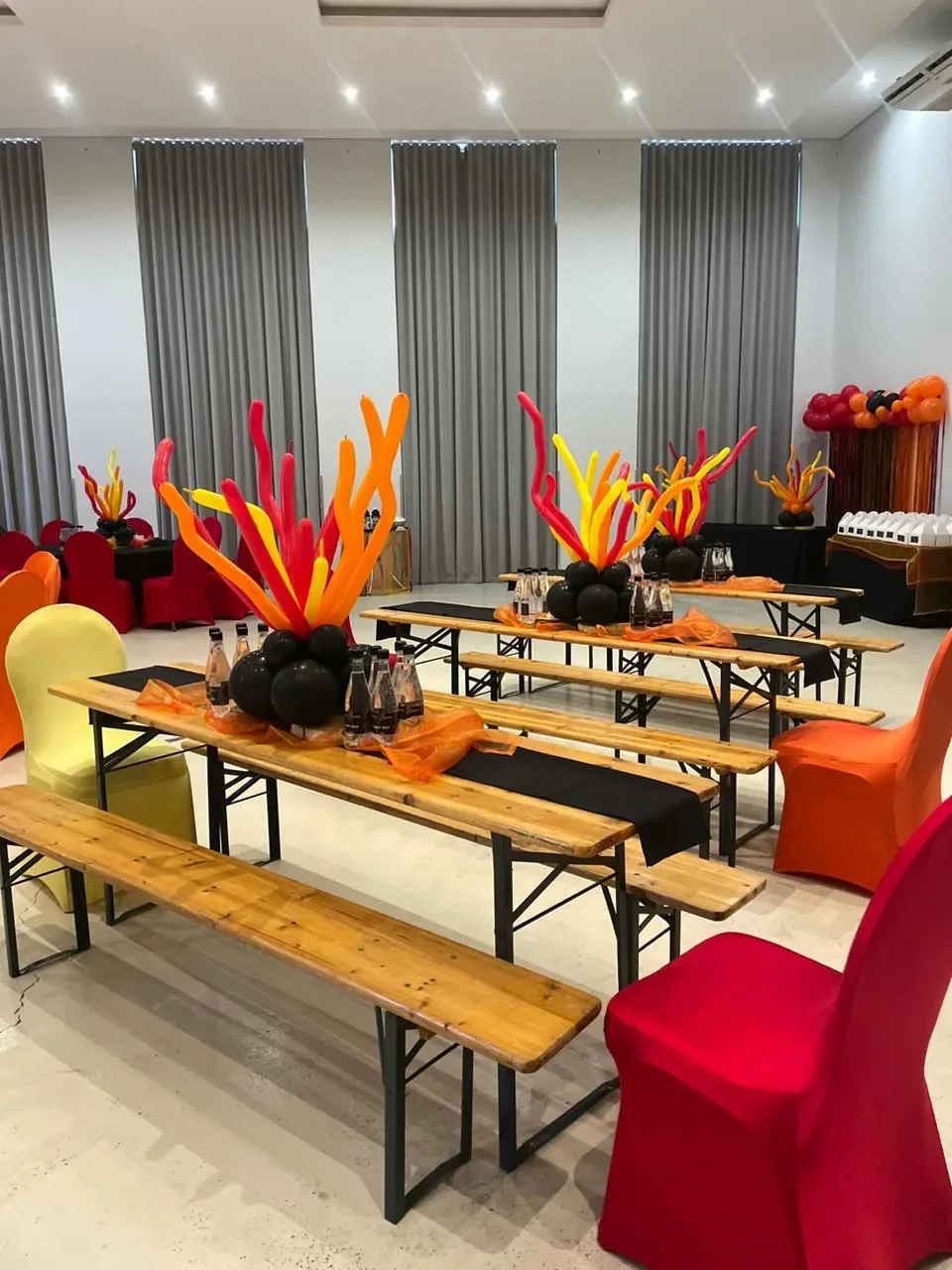 Wooden beer bench sets with colourful balloon centrepieces at an indoor party