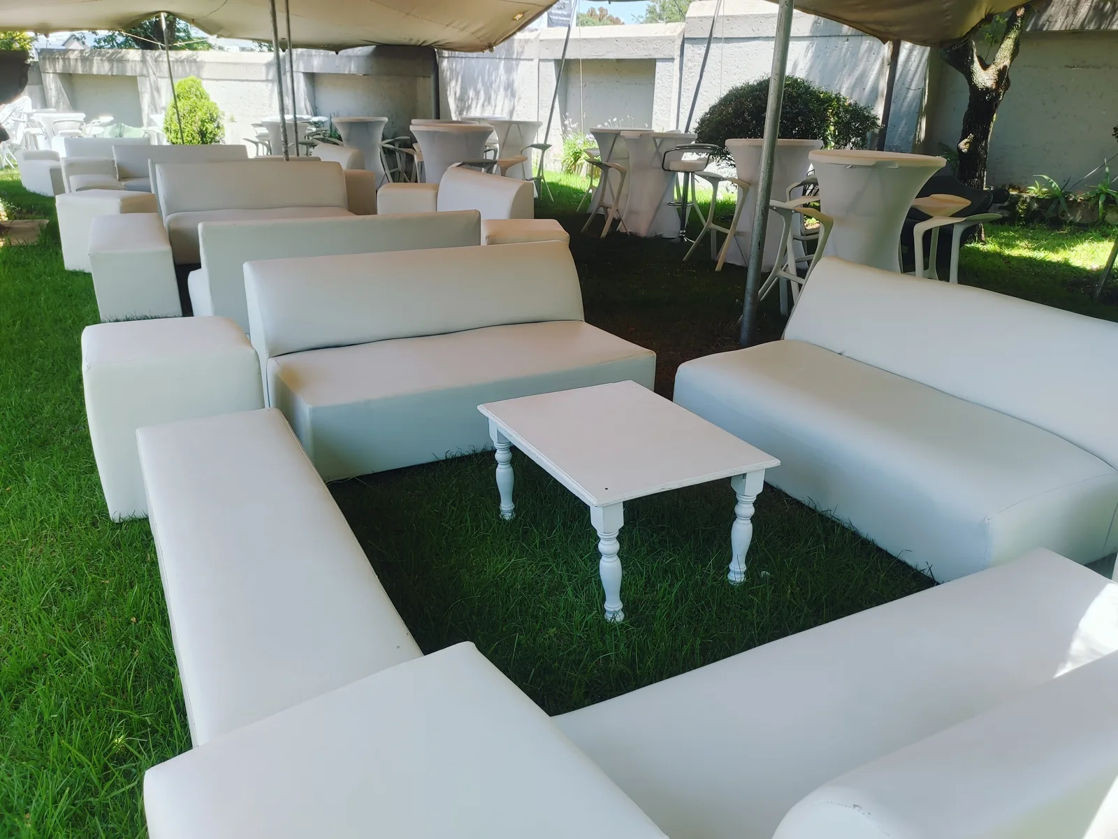 White lounge suites and coffee tables beneath a beige stretch tent
