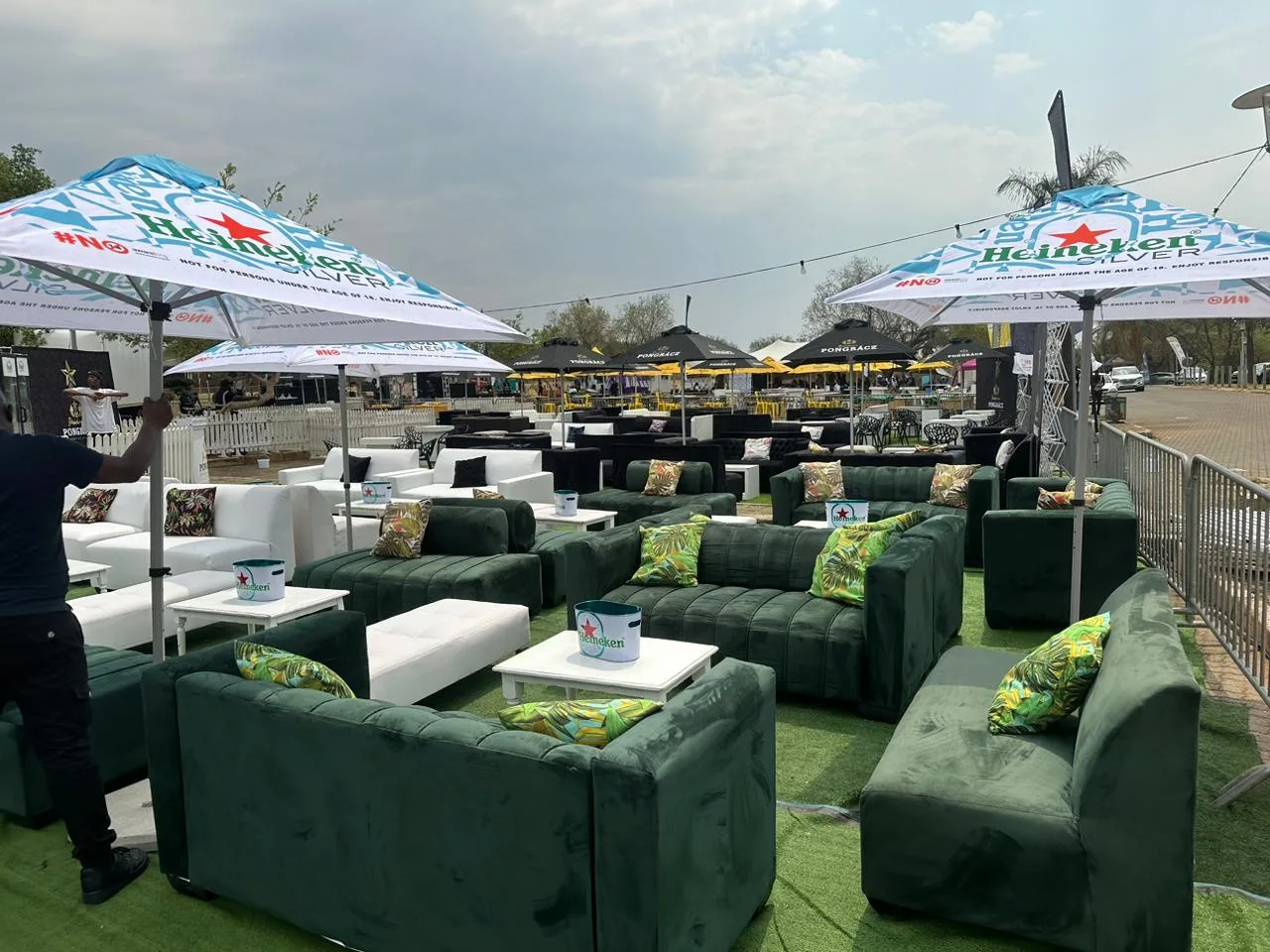 Green velvet couches and black ottomans arranged for an outdoor event